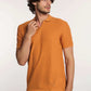 Man wearing textured orange polo shirt and blue jeans on white background