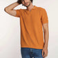 Man wearing short sleeve orange textured polo shirt and blue jeans on white background