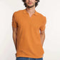 Man wearing textured orange short sleeve polo shirt and blue jeans against white background