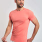 Man wearing fitted coral short-sleeve t-shirt and white pants on plain background