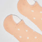 Peach low-cut socks with white polka dots on a plain background