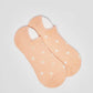 Peach ankle socks with white polka dots on a plain background