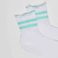 White socks with green stripes and ruffled cuffs on a plain background
