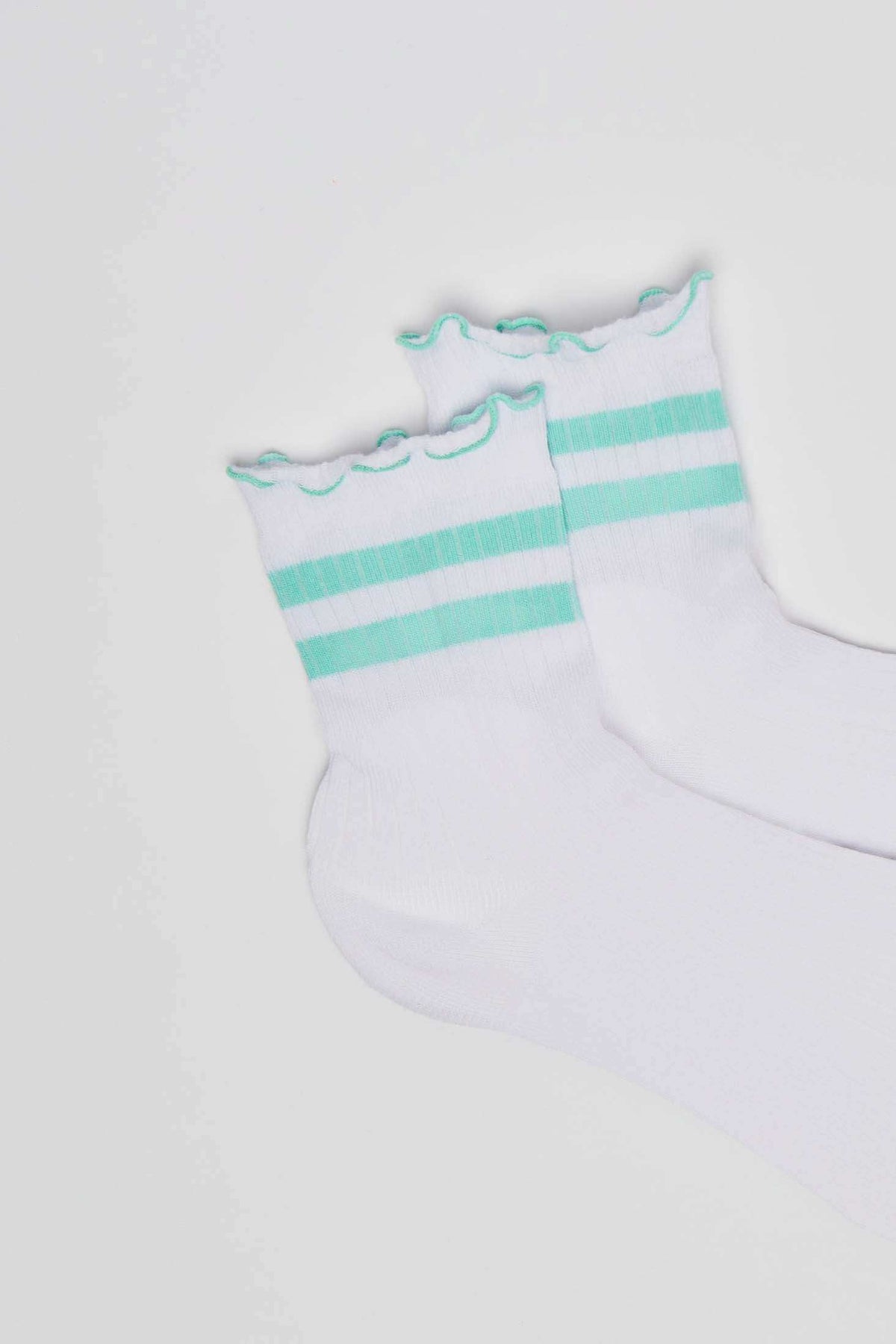 White socks with green stripes and ruffled cuffs on a plain background