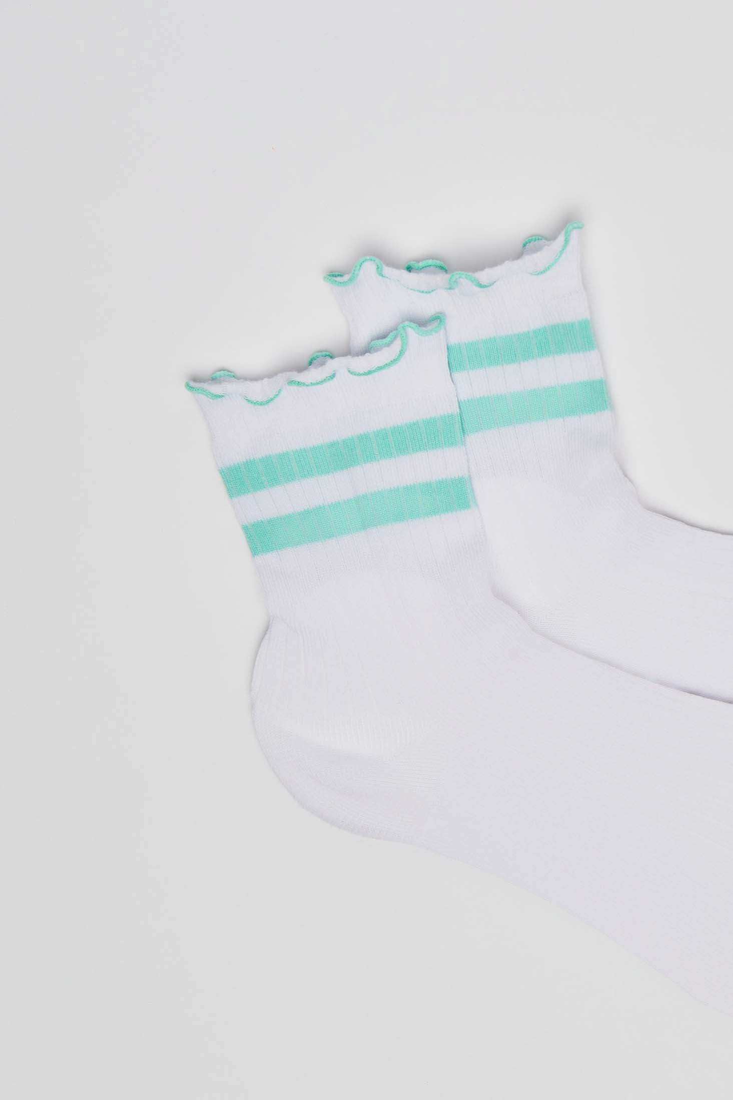 White socks with green stripes and ruffled cuffs on a plain background