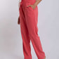 Woman wearing coral pink drawstring pants with side pockets and beige heeled sandals