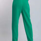 Woman wearing high-waisted green trousers and black heels, rear view