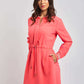Woman wearing a coral long sleeve casual dress with drawstring waist, posing on light background