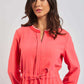 Woman in coral long sleeve dress with tie waist and white trim collar, urban casual style