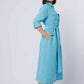 Woman wearing light blue belted shirt dress with long sleeves and pockets, casual style