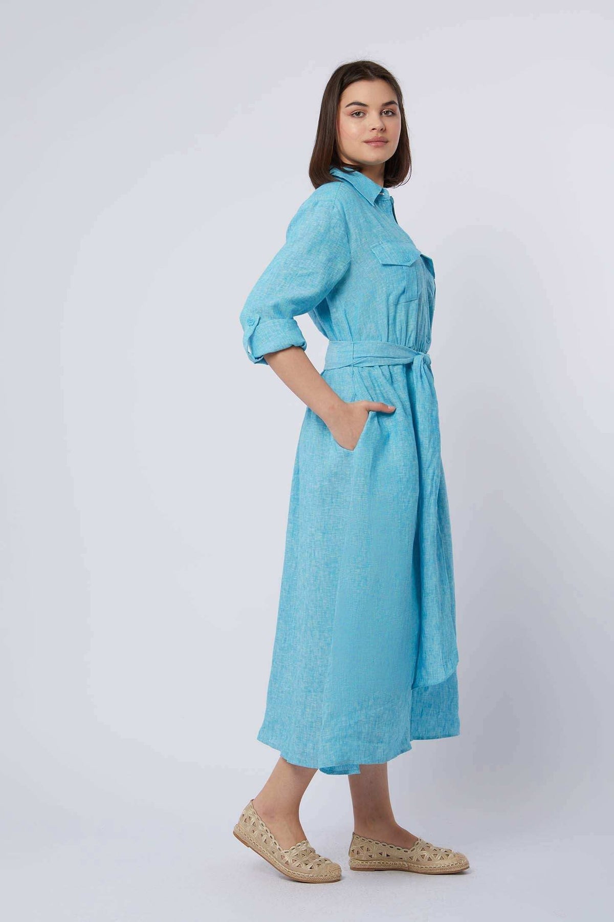 Woman wearing light blue belted shirt dress with long sleeves and pockets, casual style