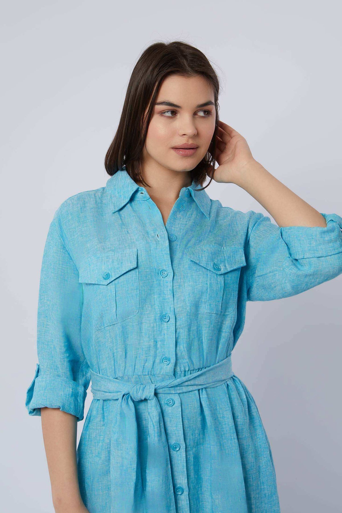 Woman wearing light blue belted long sleeve shirt dress with chest pockets