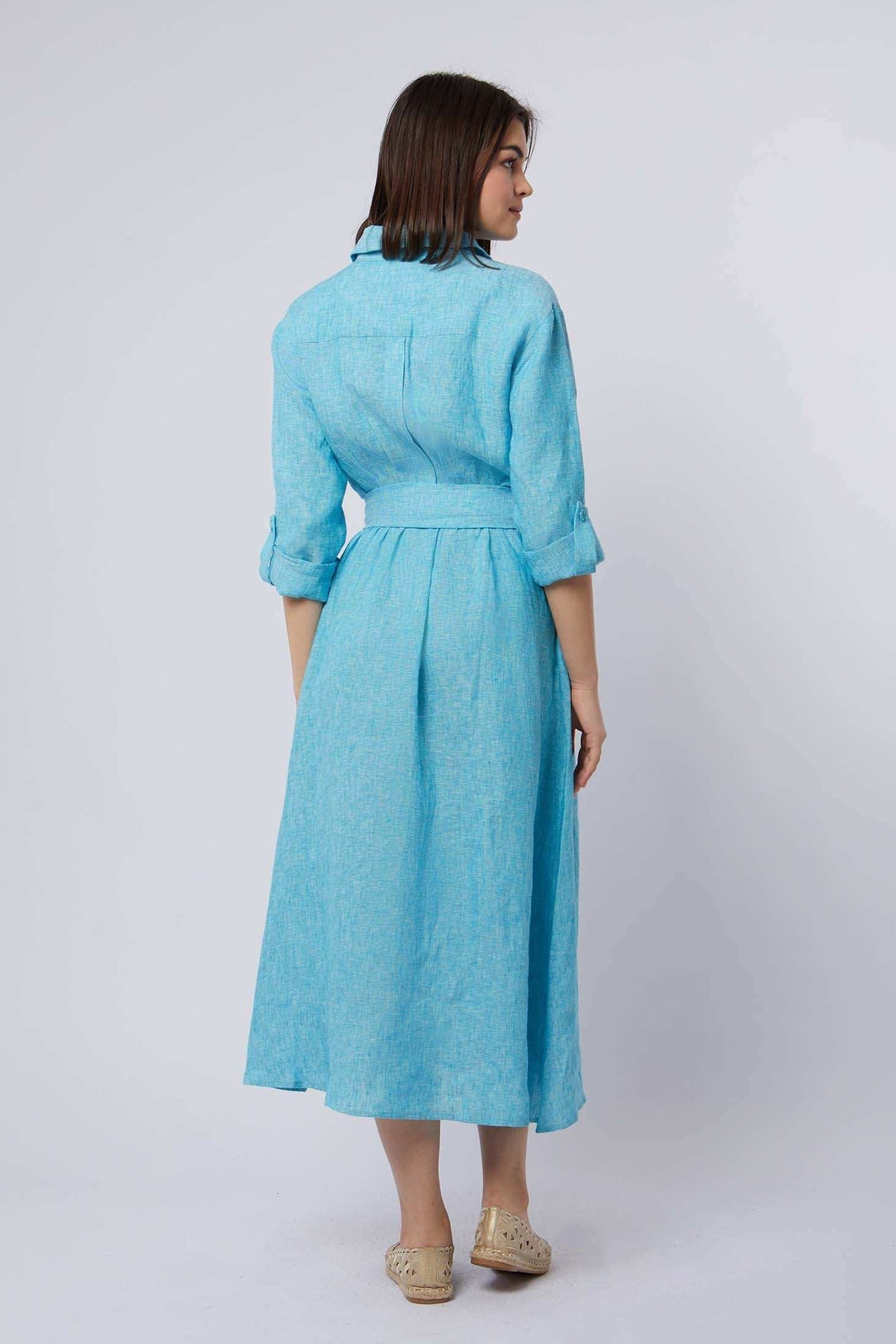 Woman wearing a light blue belted midi dress with rolled sleeves, shown from the back