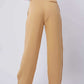Back view of woman wearing high-waisted beige wide-leg trousers and white blouse