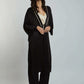 Woman wearing a black long cardigan with white trim, cream blouse, wide-leg pants, and heels