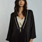 Woman wearing a black satin robe with white trim over a cream top, casual elegant fashion