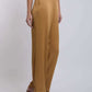 Woman wearing mustard wide-leg trousers with side pockets and tan heeled sandals