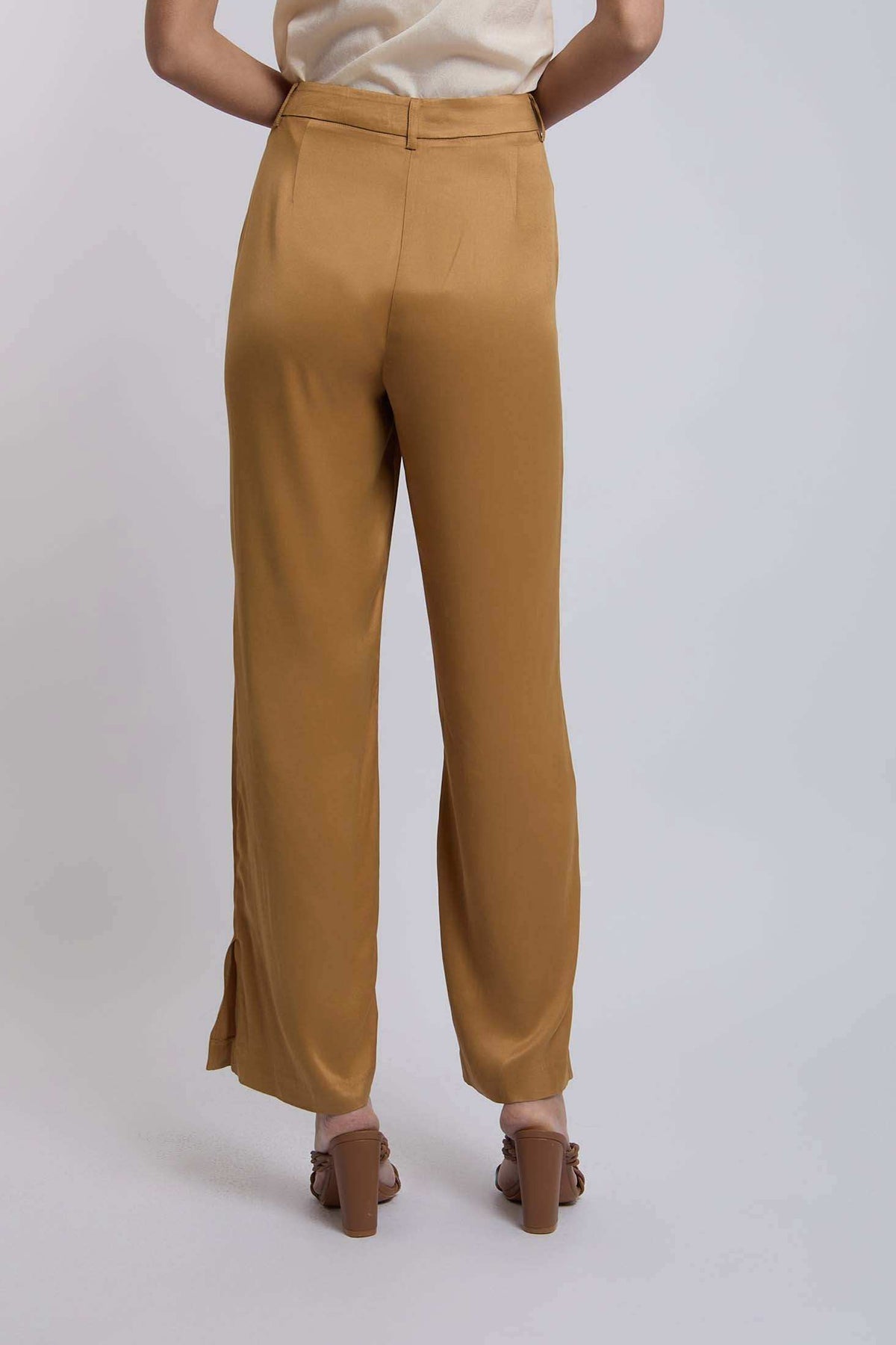 Woman wearing high-waisted mustard yellow wide-leg trousers and heeled sandals