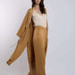 Woman wearing tan wide-leg pants, matching long coat, and cream blouse, fashion outfit