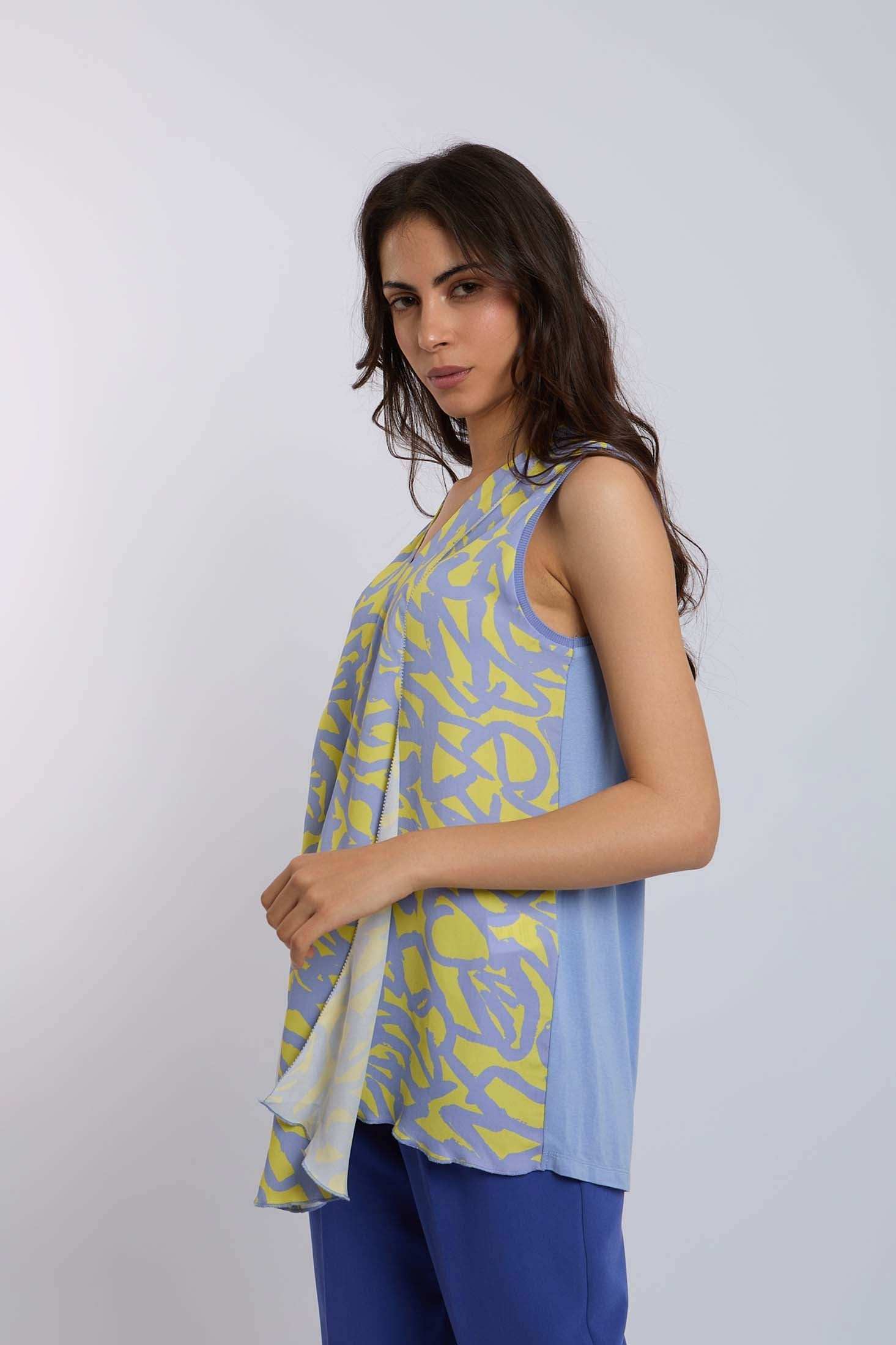 Woman wearing sleeveless abstract print blue and yellow top with blue pants