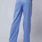 Woman wearing high-waisted light blue wide-leg trousers with side pockets