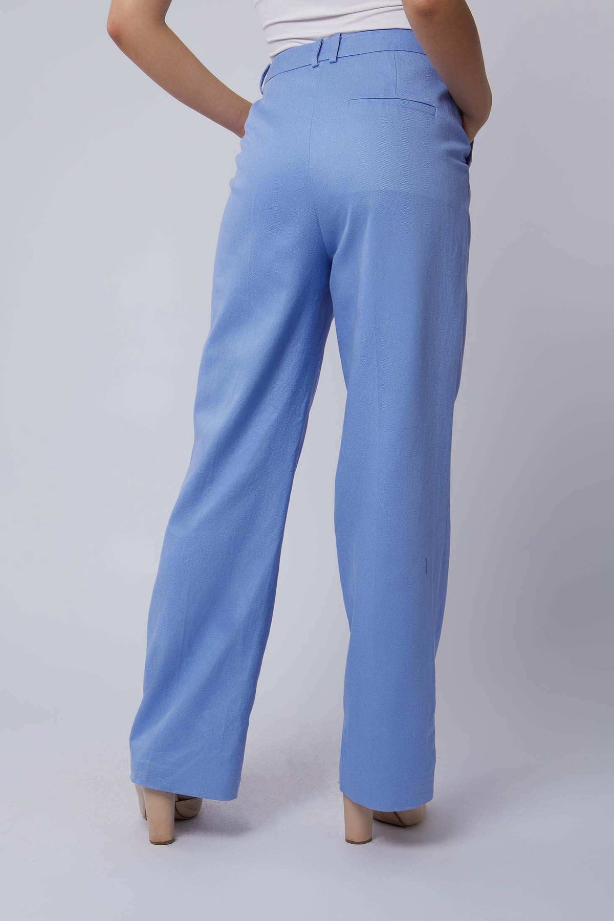 Woman wearing high-waisted light blue wide-leg trousers with side pockets