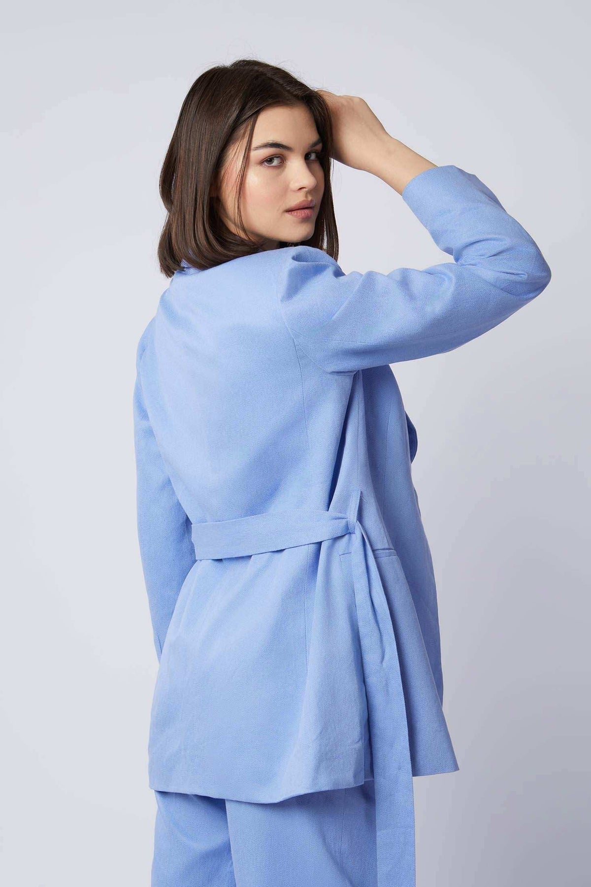 Woman in light blue belted blazer and pants set, back view, casual fashion look