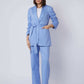 Woman wearing a light blue belted pantsuit with white top and beige heels