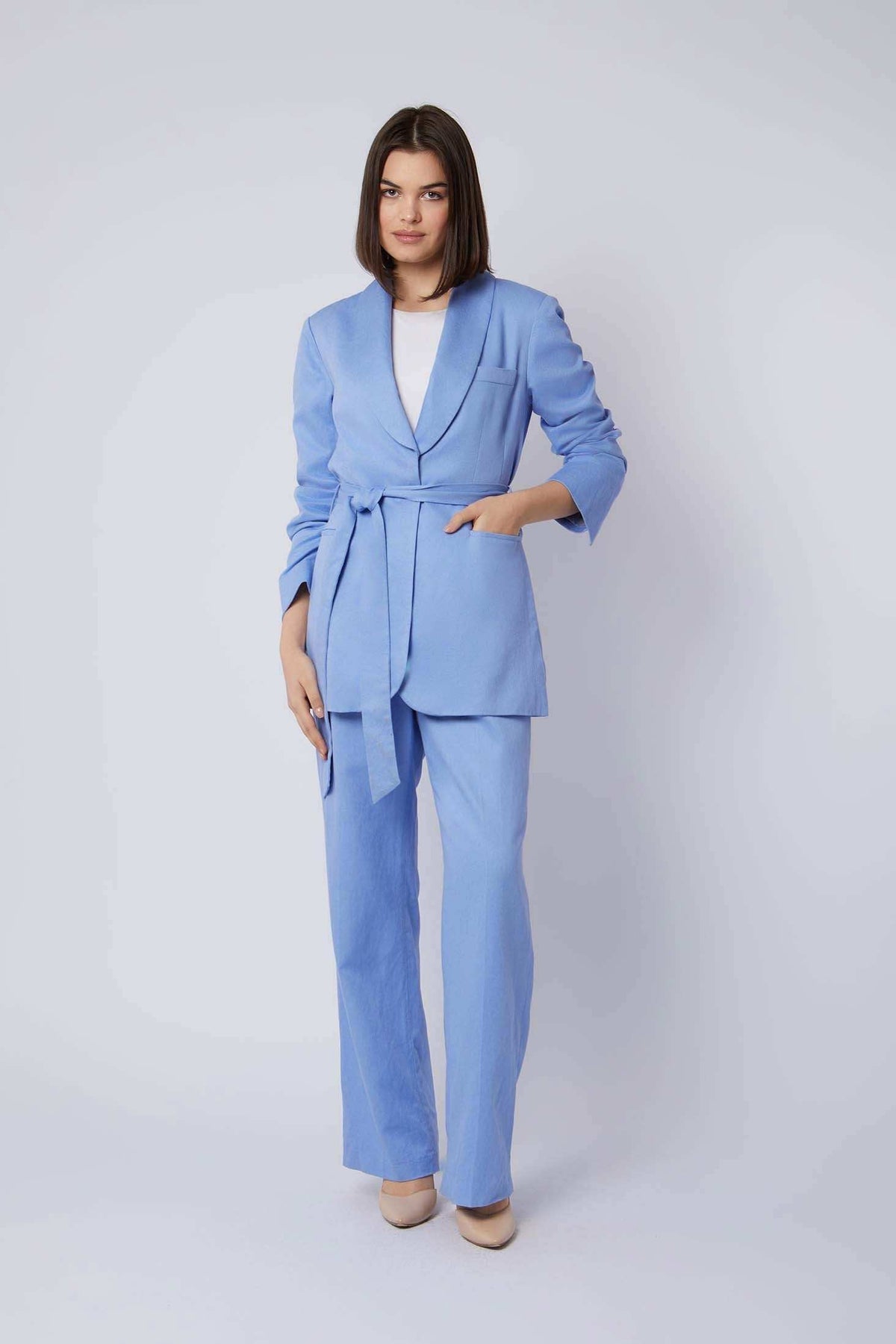 Woman wearing a light blue belted pantsuit with white top and beige heels