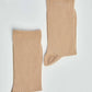 Pair of beige ribbed socks on a plain white background