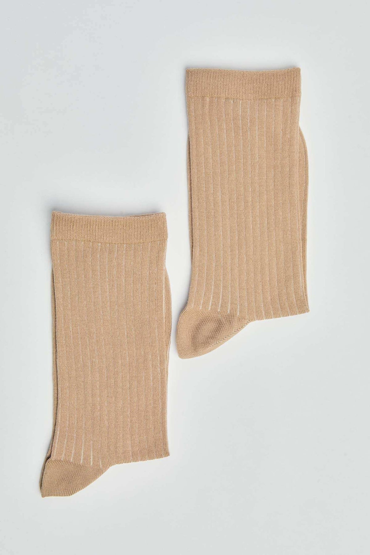 Pair of beige ribbed socks on a plain white background