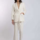 Woman wearing cream tailored linen blazer and wide-leg pants set on plain background